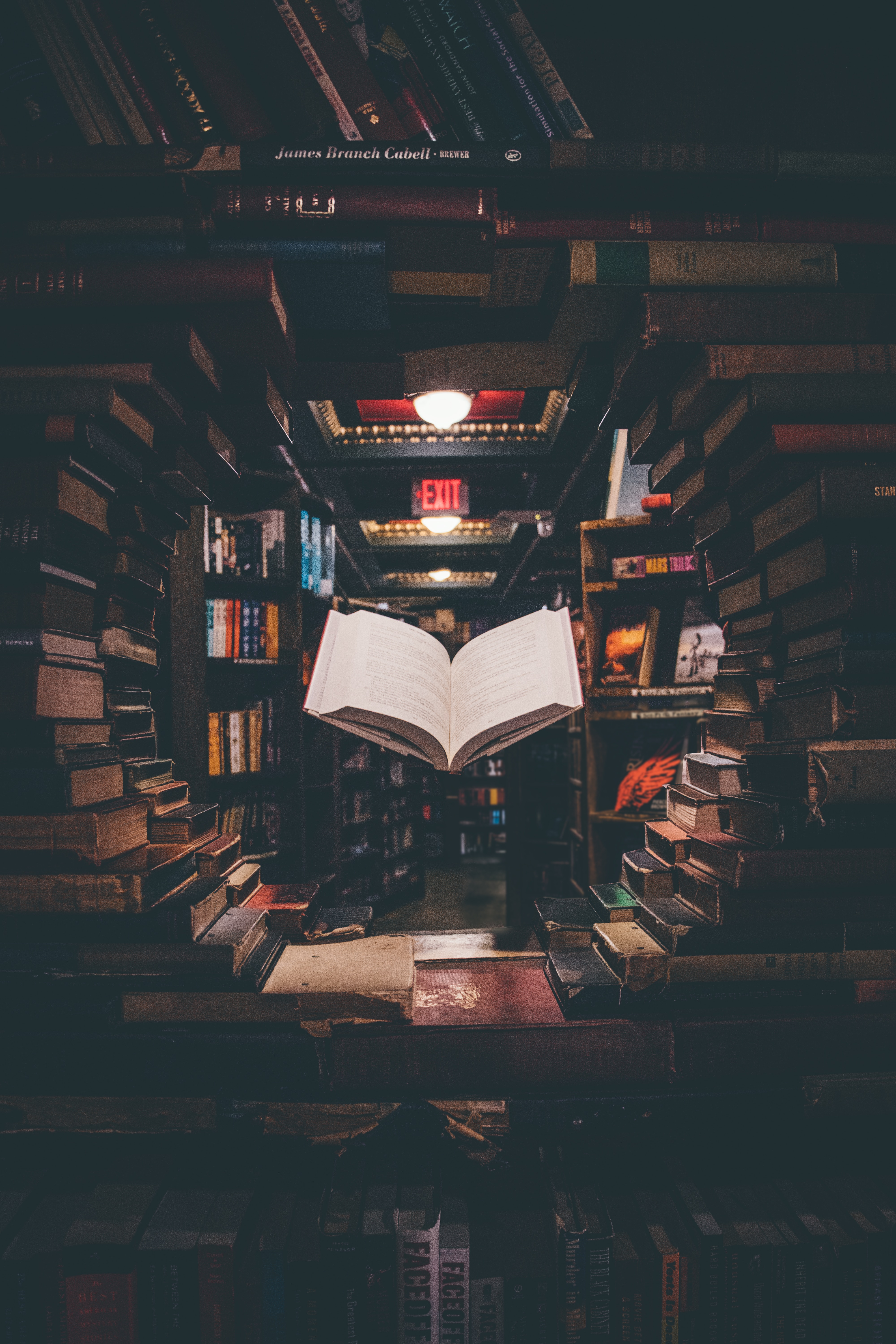 The Works Service Image: Book suspended in a circle of stacked books, with light shining on it